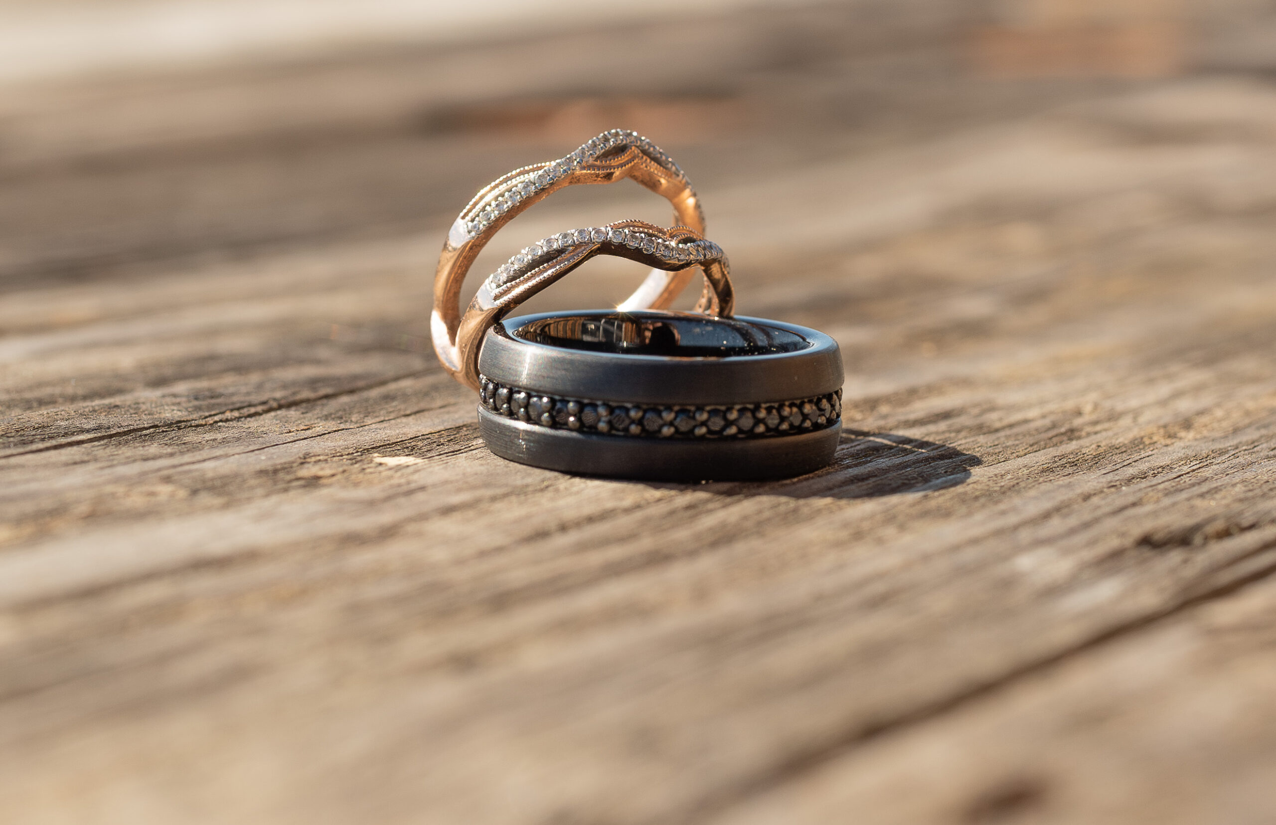 Bride and Groom rings on a wooden spool with nature in the background.