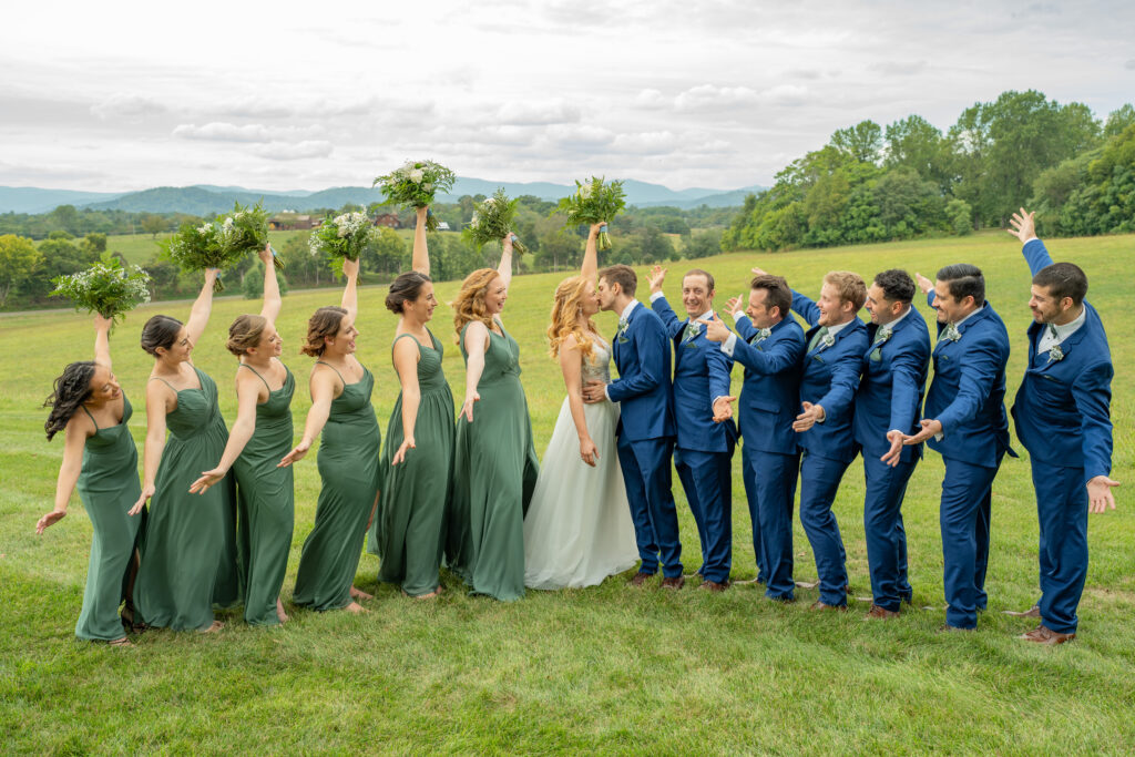 A whole wedding party cheering for the wedding couple with the mountains in the background.