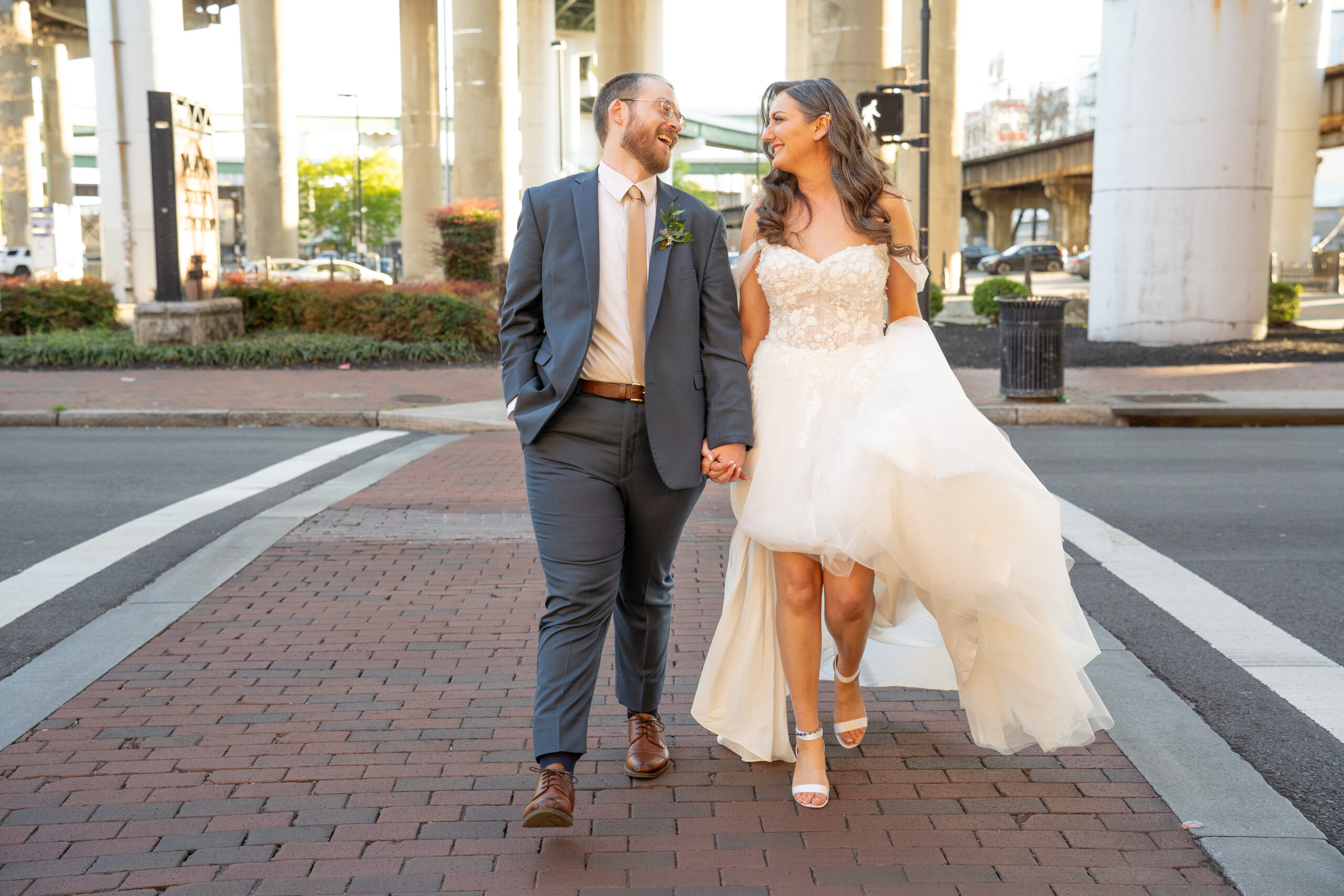 A groom is leading his bride across the street at main street station in Richmond, Virginia after their wedding ceremony.