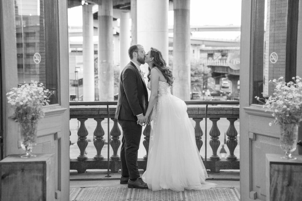 A bride and groom kiss with a door as their frame for the photo.