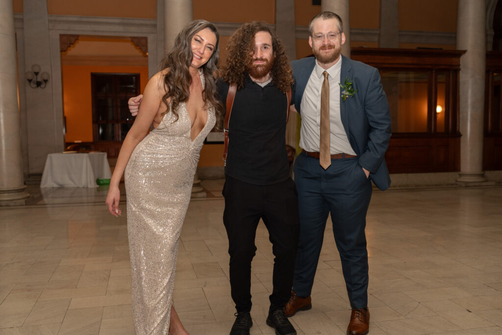 Mason Jesmer posing with a wedding couple who just got married at main street station.