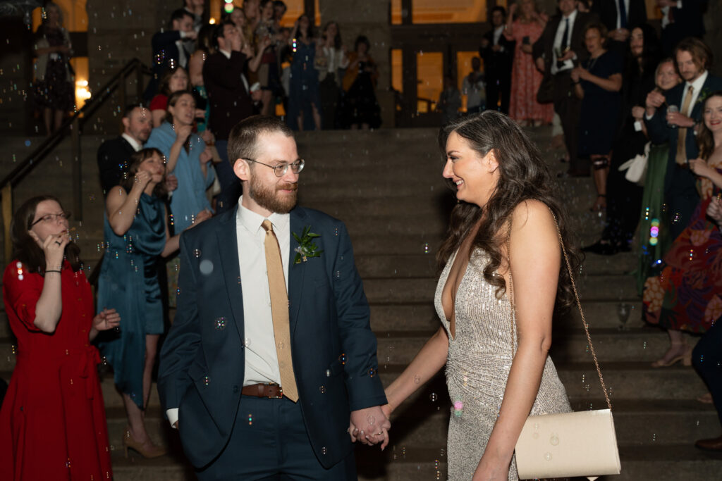 A bride and groom walk down Main Street Station stairs to do a bubble exit to end their wedding night.