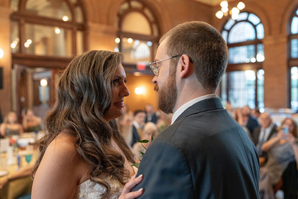 A bride smiles at her new husband during their first dance at their wedding reception. 