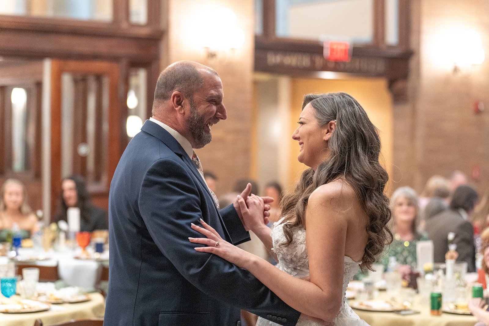 A bride smiles at her dad during their father daughter dance at their wedding reception. 