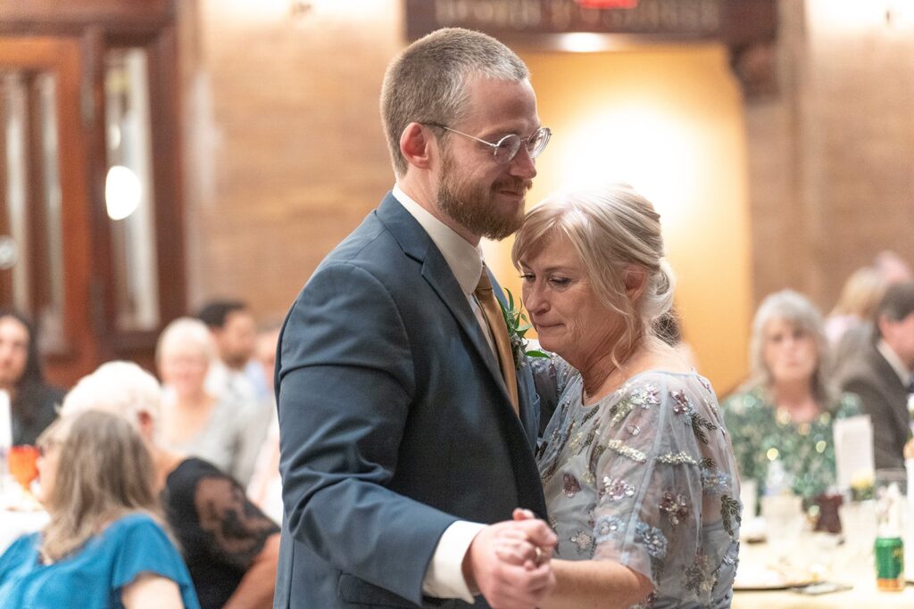 A groom smiles at his mom during their mother and son dance at their wedding reception. 