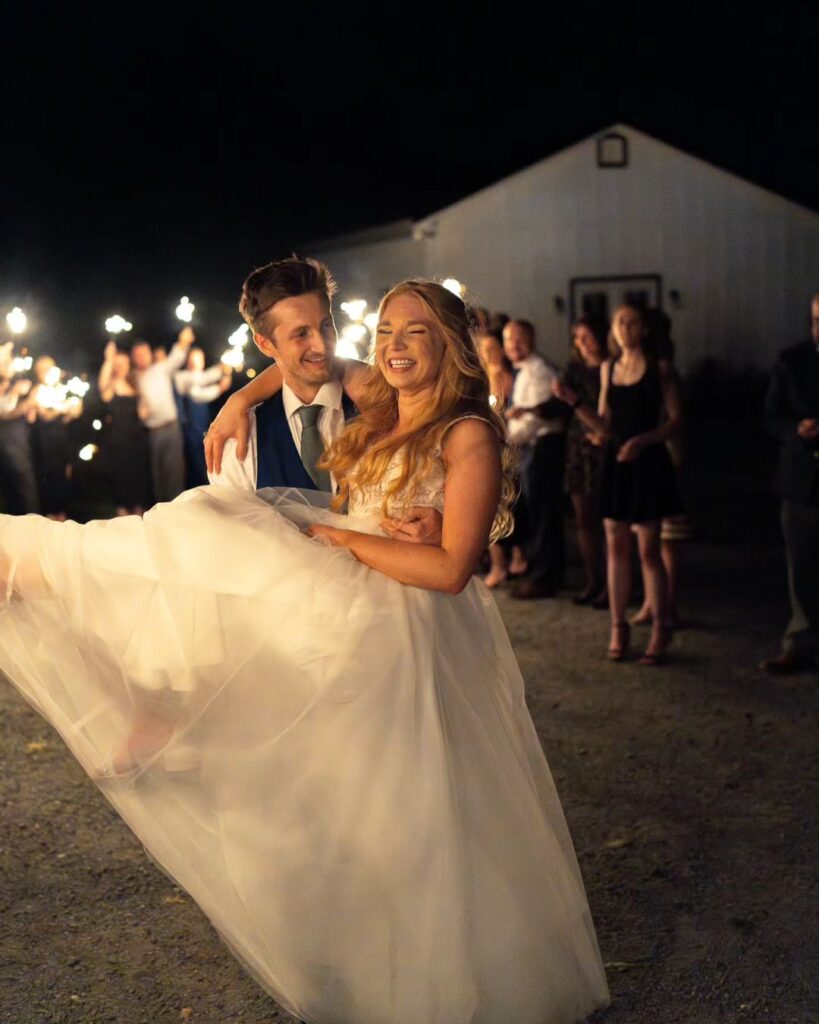 Groom is carrying the bride during their wedding day sparkler exit 