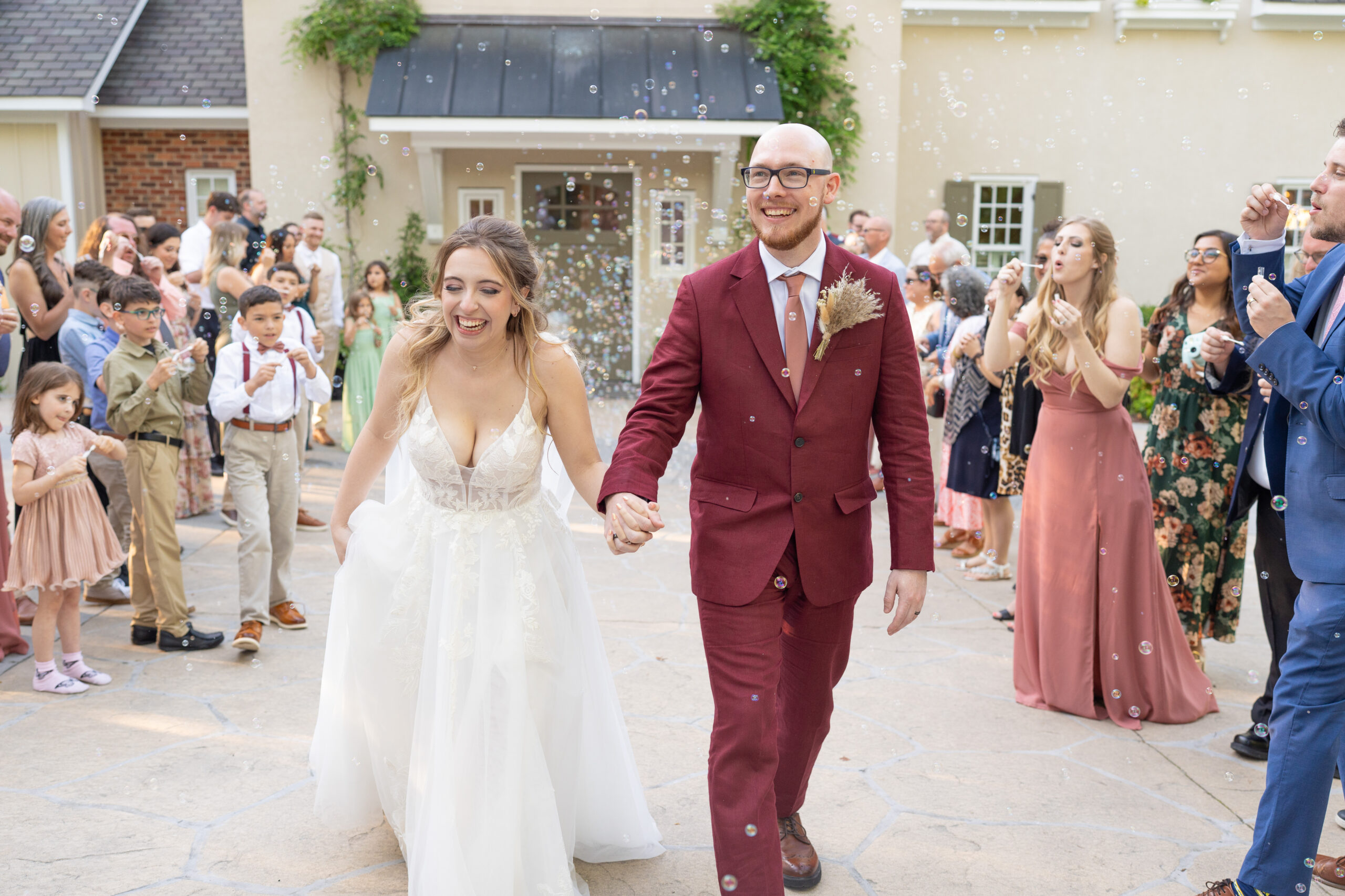 Bride and groom laughing while walking through a bubble exit surrounded by guests at The Mill at Fine Creek in Powhatan, Virginia