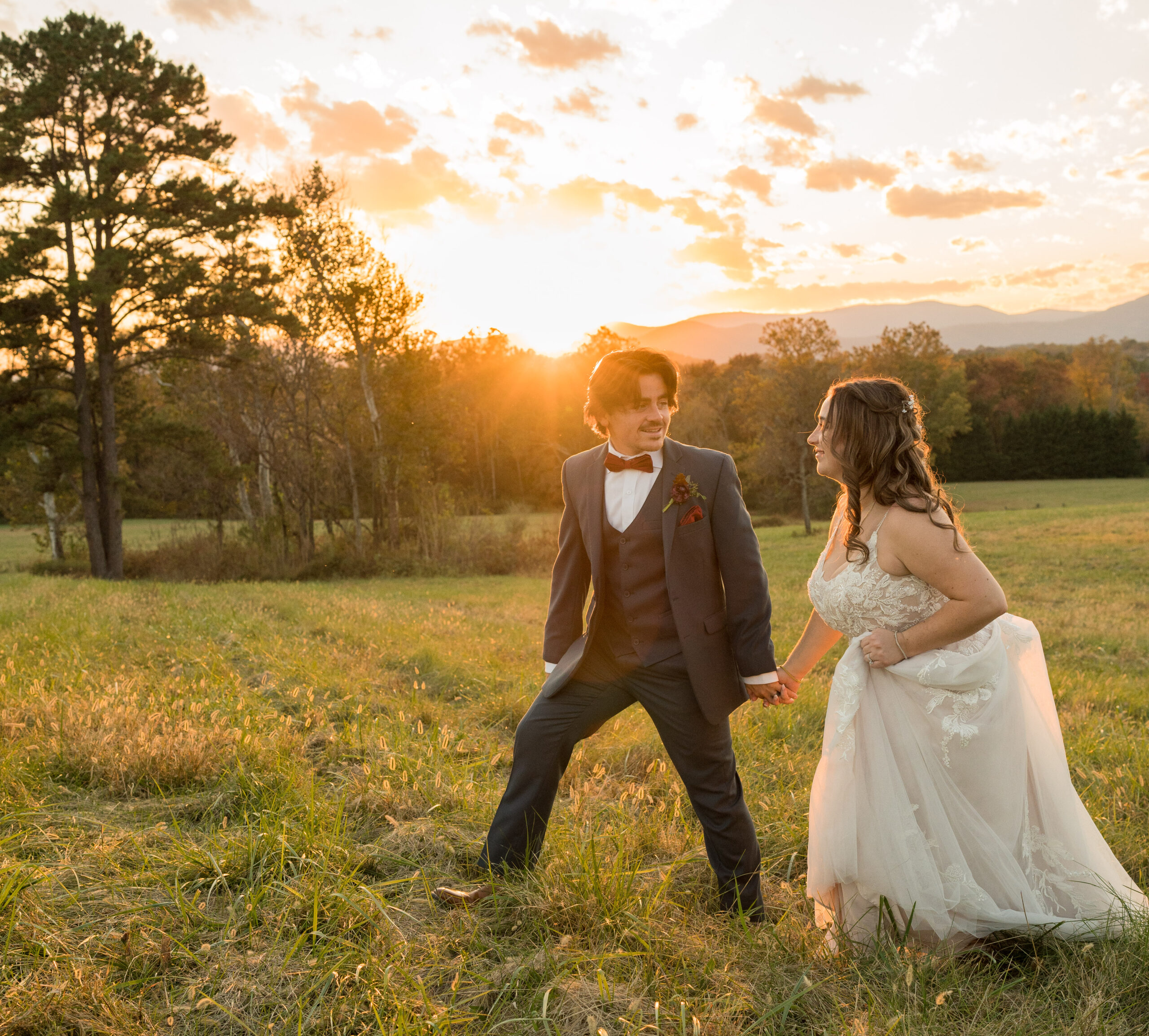 Bride and groom holding hands and smiling during golden hour wedding portraits at The Barn at Edgewood in Stanardsville, Virginia, with the Blue Ridge Mountains in the background
