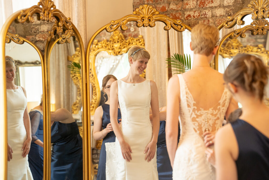 Bride getting ready in the bridal suite at Mankin Mansion, reflected in ornate gold mirror. Photographed by Richmond wedding photographer Mason Jesmer